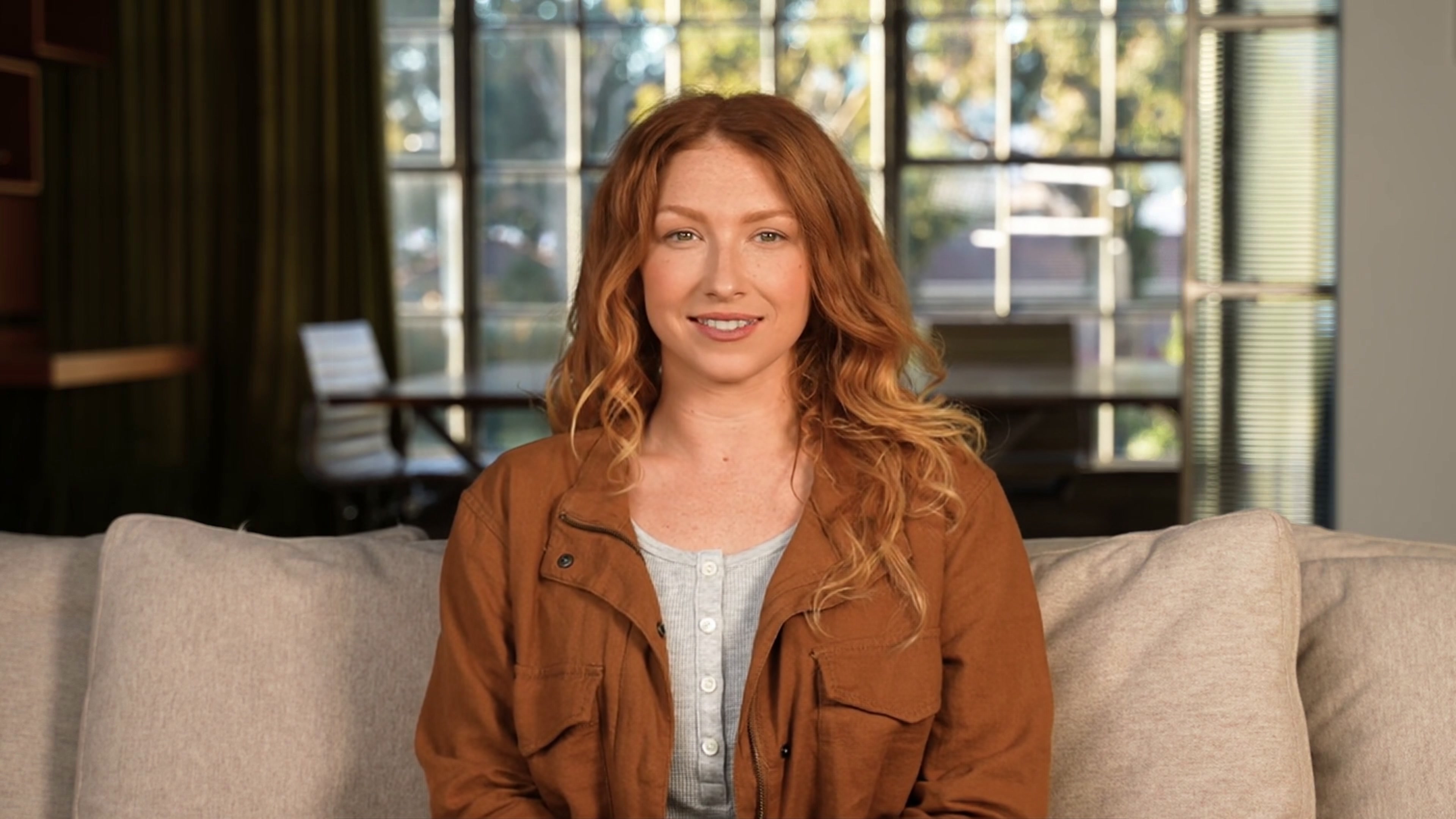 Jackie, the AI avatar guide, with red hair in a bright office setting